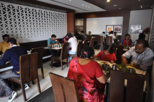 un grupo de personas sentadas en mesas en un restaurante en Vijey Hotels, en Tiruchchirāppalli