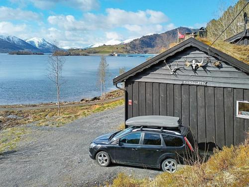 a car parked next to a building next to a lake at 4 person holiday home in ydegard in Torvikbukt