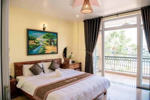 a bedroom with a large bed and a balcony at Orchid Riverside Villa in Hue