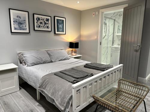 1 dormitorio con cama, silla y ducha en Luxury Detached Studio Apartment - Free Super Fast WiFi - Free Parking - 15 Mins from Luton Airport, en Luton