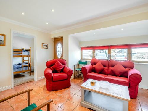sala de estar con sofá rojo y 2 sillas en Appletree Cottage en Saint Osyth