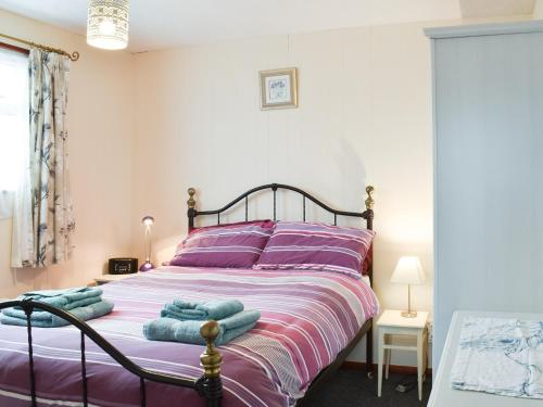 a bedroom with a bed with purple sheets and purple pillows at Pintail in Brundall