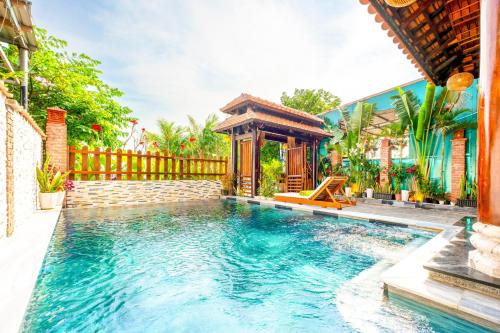 Eco Wooden villa Hoi An في هوي ان: مسبح مع شرفة بجوار منزل