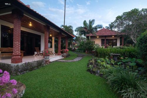 una casa con un patio con césped verde en Cabé Bali, en Jasri