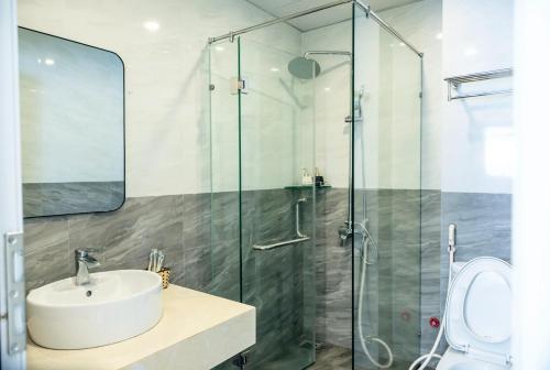 a bathroom with a sink and a glass shower at Orchid Riverside Villa in Hue