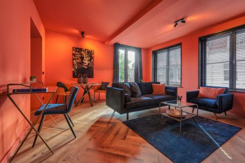 een woonkamer met oranje muren en stoelen en een tafel bij The Roosevelt Apartments in Middelburg