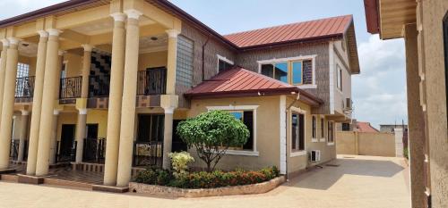 ein Haus mit Säulen und einem roten Dach in der Unterkunft OKF OBOUBA APARTMENT in Kumasi