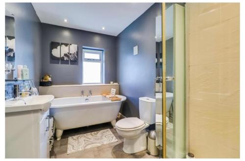 a bathroom with a tub and a toilet and a sink at House of Kaima - 6 bed detached in Dewsbury