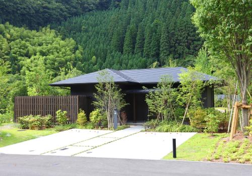 a black building with a driveway in front of a mountain at yabenomori in Miyanoo