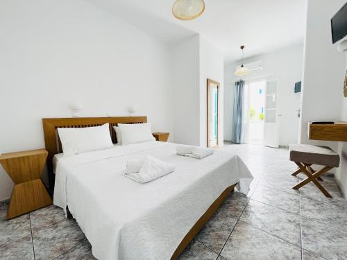 a white bedroom with a large bed with white sheets at Cyclades Blue in Ornos