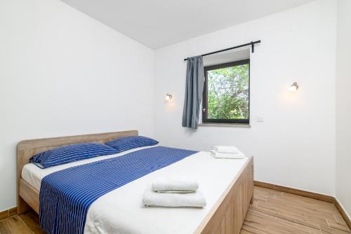 a bedroom with a bed with blue and white sheets and a window at Apartment Premantura 2228a in Premantura