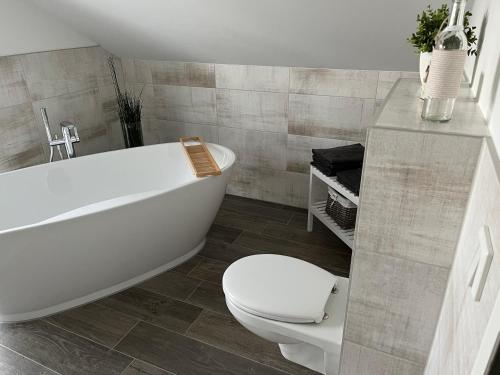 a bathroom with a white tub and a toilet at Ferienhaus Oskar 100m Entfernung zum See/Strand in Löbnitz