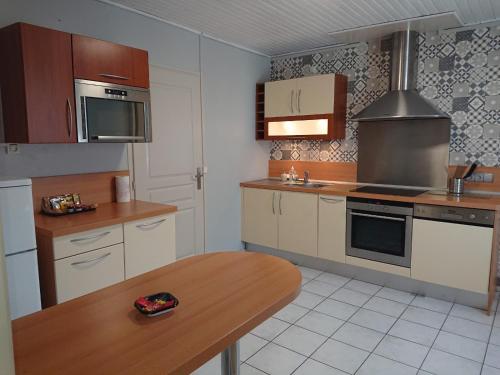 a kitchen with wooden cabinets and a wooden table at chambre privée à BORDEAUX PELLEGRIN in Bordeaux