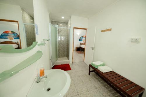 y baño blanco con lavabo y ducha. en Maison Du Soleil Self Catering, en Anse Possession