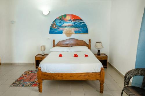 una camera da letto con un letto con due fiori rossi sopra di Maison Du Soleil Self Catering a Anse Possession
