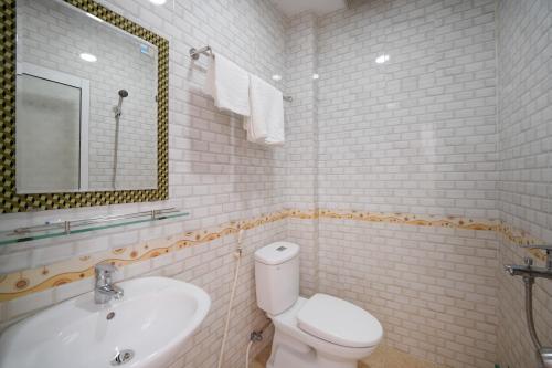 a bathroom with a sink and a toilet and a mirror at Ris Hotel Đà Nẵng in Da Nang