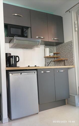 cocina con armarios grises y encimera en Le douillet-Studio avec cour extérieure, en Montauban