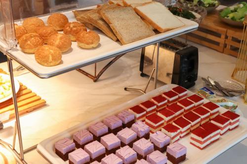 Una vitrina con pasteles y panes sobre una mesa. en Starlit sky Hotel - Shenzhen Luohu Baoneng Center Branch, en Shenzhen