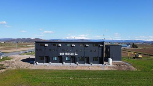 a large black building with mountains in the background at Yadoya YADOKARI 2nd in Pippu