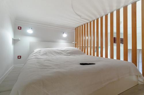 a bedroom with a white bed with a wooden headboard at Green Gallery on a Main Square in Zagreb