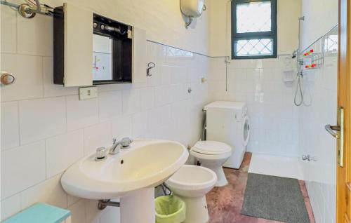 Baño blanco con lavabo y aseo en Stunning Home In Orgosolo With Wifi, en Orgosolo
