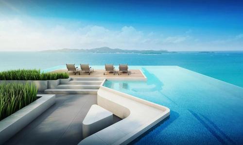 une piscine avec des chaises et l'océan dans l'établissement Andromeda Seaview Condo Near Beach, à Pattaya (sud)