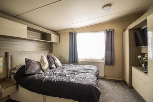 Rúm í herbergi á Modern 6 Berth Caravan With Decking At Cherry Tree Park In Norfolk Ref 70324c