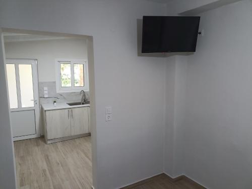 a white kitchen with a sink and a tv on a wall at palm-tree in Arkoudi