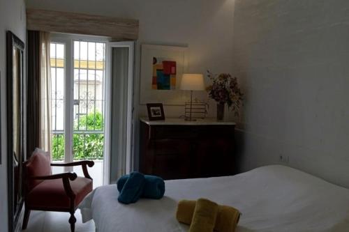 um quarto com uma cama, uma cadeira e uma janela em El patio de Nervión. em Sevilha