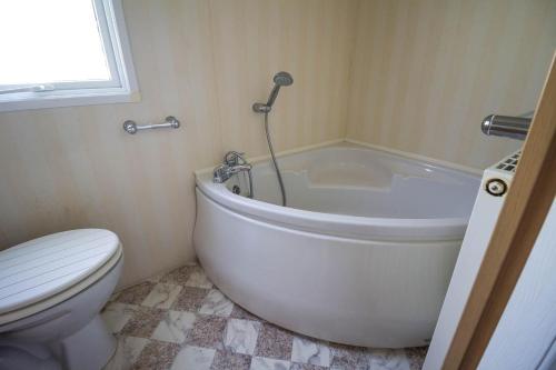 a bathroom with a white tub and a toilet at Stunning 6 Berth Caravan At Manor Park In Hunstanton Norfolk Ref 23194k in Hunstanton