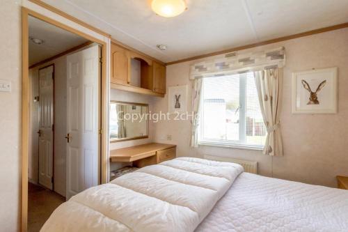 a bedroom with a large white bed and a window at Stunning 6 Berth Caravan At Manor Park In Hunstanton Norfolk Ref 23194k in Hunstanton