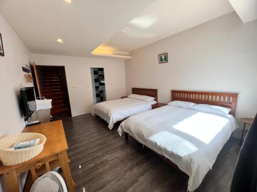 a bedroom with two beds and a table and a television at Golden flower Homestay in Yuli