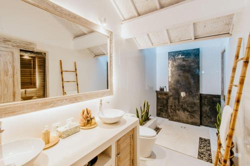 een badkamer met een wastafel, een toilet en een spiegel bij Villa Lanie Lembongan in Nusa Lembongan