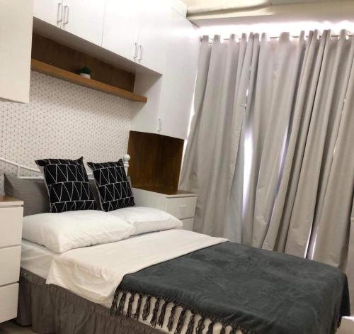 a bedroom with a bed and a window with curtains at Cozy Flexi 1BR or 2BR condo at Southmall Las Pinas in Manila
