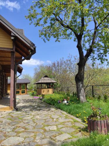a stone walkway next to a house with a tree at Nad Cheremoshem in Tyudiv