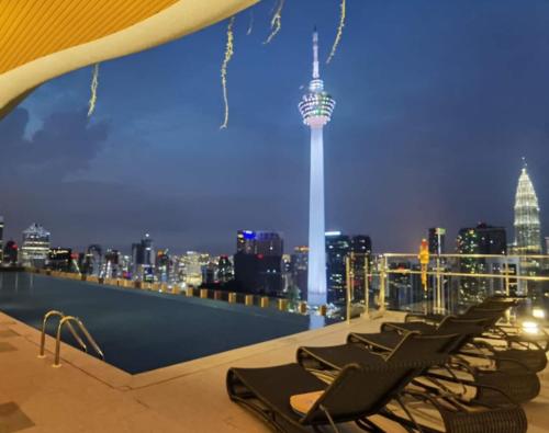 a row of lounge chairs on the roof of a building with a city skyline at Ceylonz Suites KL City by One39KL in Kuala Lumpur