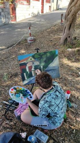 a person sitting on the ground with a painting at Dva lava in Podaca