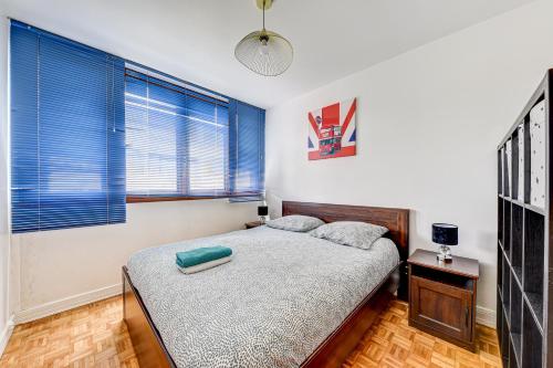 - une chambre avec un lit et 2 fenêtres avec des stores bleus dans l'établissement Grand appartement calme à 30 min de Paris, à Morsang-sur-Orge