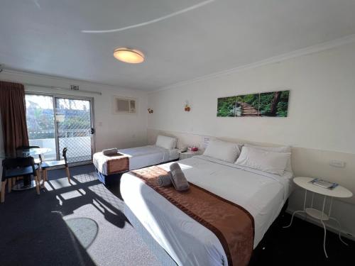 パースにあるEcono Lodge Rivervaleのベッド2台と窓が備わるホテルルームです。