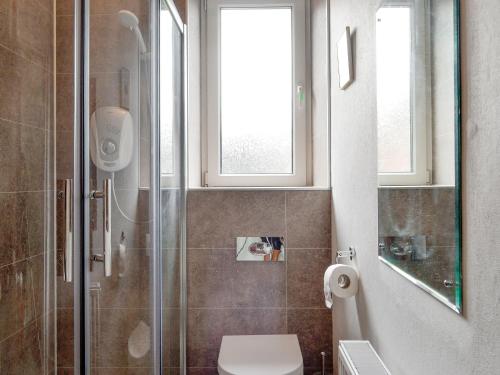 a bathroom with a shower and a toilet and windows at Cochrane House in Kirkcudbright