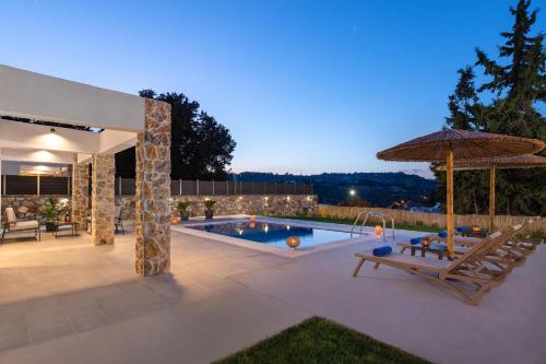 un patio con piscina, sombrilla y sillas en Aiora Luxury Villas, en Afantou