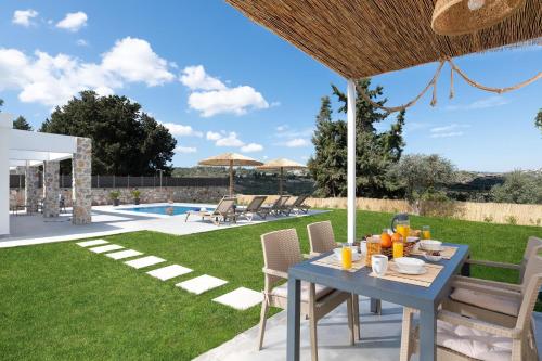 een patio met een tafel en stoelen en een zwembad bij Aiora Luxury Villas in Afantou