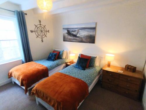 a bedroom with two beds and a painting on the wall at Darnholm Cottage in Robin Hood's Bay