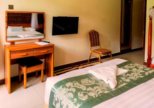 a bedroom with a bed and a desk and a mirror at Kalya Courts Hotel Fort Portal in Fort Portal