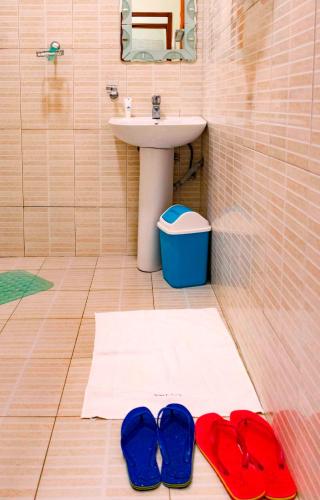 a bathroom with two blue flip flops and a sink at Kalya Courts Hotel Fort Portal in Fort Portal