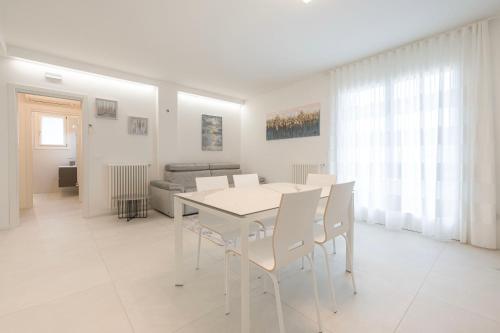 a white dining room with a white table and chairs at Residence Luxury Elisabeth con garage in Caorle