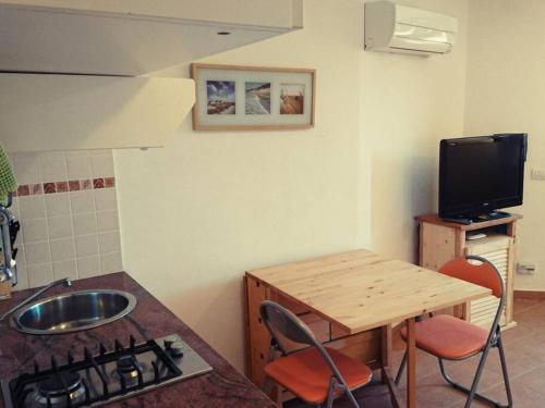 a kitchen with a sink and a table and a tv at Monolocale La Maddalena in La Maddalena