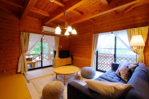 a living room with a blue couch and a table at Kurasako Onsen Sakura in Minamioguni