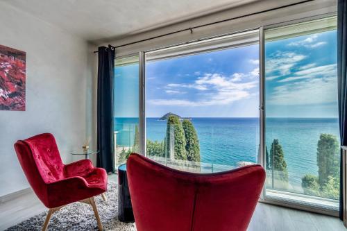 a living room with a red chair and a large window at Baba Residences in Alassio