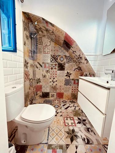 a bathroom with a toilet and a mosaic tile wall at Casa mi sùeño azul in Torrox